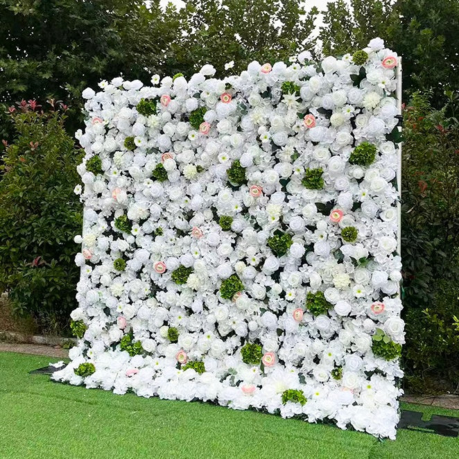 Floral wall decoration with white, green, and pink flowers on a grassy area.