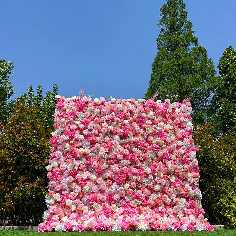 Floral wall made of pink, white, and red flowers against a blue sky with trees in the background